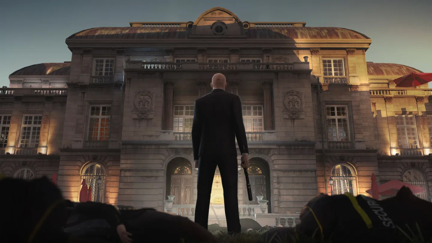 HITMAN publisher screenshot showing Agent 47 facing a lit palace at dusk.